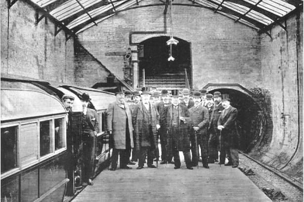 Officials gathering for a photograph on the opening day of the Glasgow District Subway system back in 1896 with the train pictured to the left of the photo. 