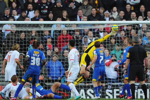 Jon Otsemobor watches on as his ‘Heel of God’ flick lofts over Neil Sullivan back in December 2012 when MK Dons beat AFC Wimbledon in the first meeting between the sides