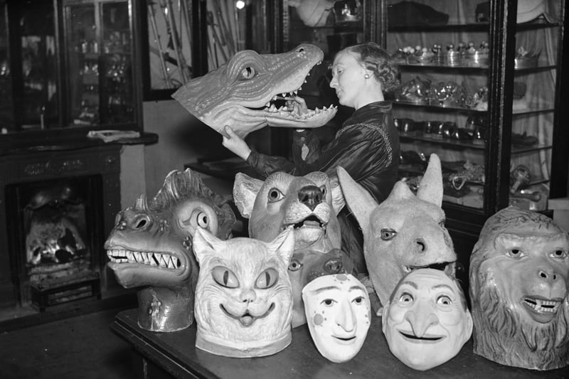 A shop assistant cleans the pantomime masks at a theatrical property store in Manchester,  in 1936
