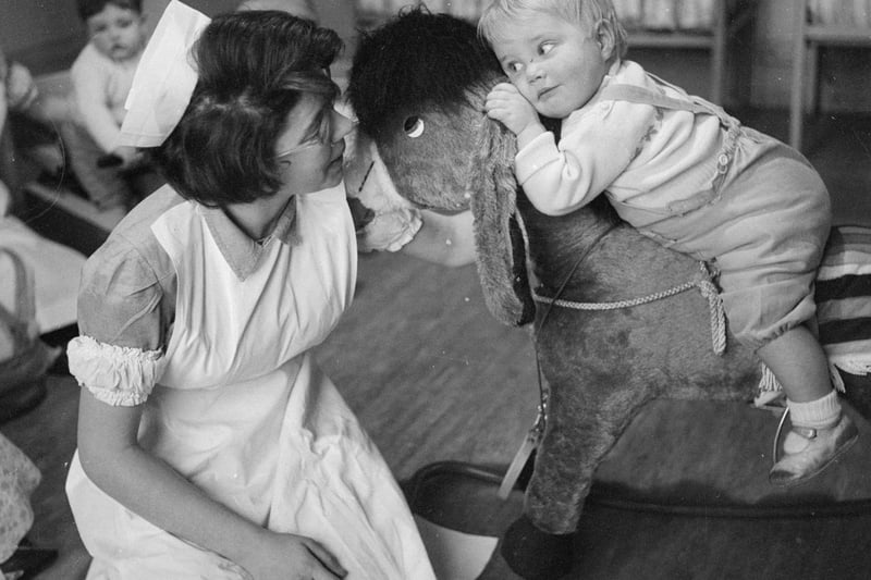 A student nurse supervises a toddler on a rocking horse at Princess Christian College for Nursery Nurses in Manchester. 