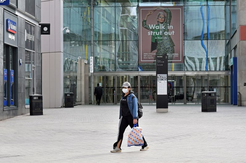 A woman wearing a protective face mask walks past a quiet Bullring Shopping Centre in Birmingham in central England on the morning of March 21, 2020, a day after the British government said it would help cover the wages of people hit by the coronavirus outbreak as it tightened restrictions to curb the spread of the disease