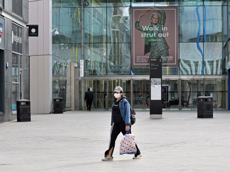 A woman wearing a protective face mask walks past a quiet Bullring Shopping Centre in Birmingham in central England on the morning of March 21, 2020, a day after the British government said it would help cover the wages of people hit by the coronavirus outbreak as it tightened restrictions to curb the spread of the disease
