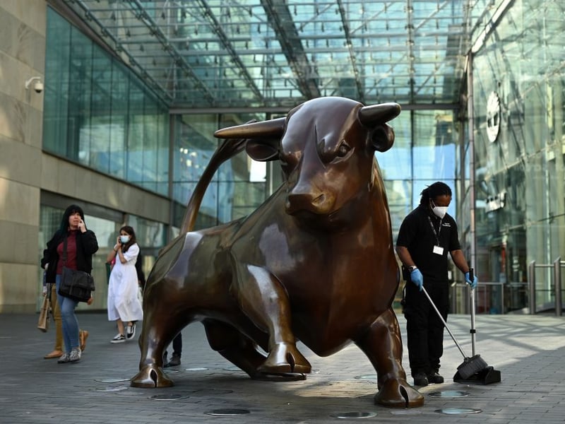 A worker wearing a face mask or covering due to the COVID-19 pandemic, sweeps the floor near a statue of a bull at the Bullring in Birmingham, central England on September 14, 2020 after the British government imposed fresh restrictions on the city after an rise in cases of the novel coronavirus