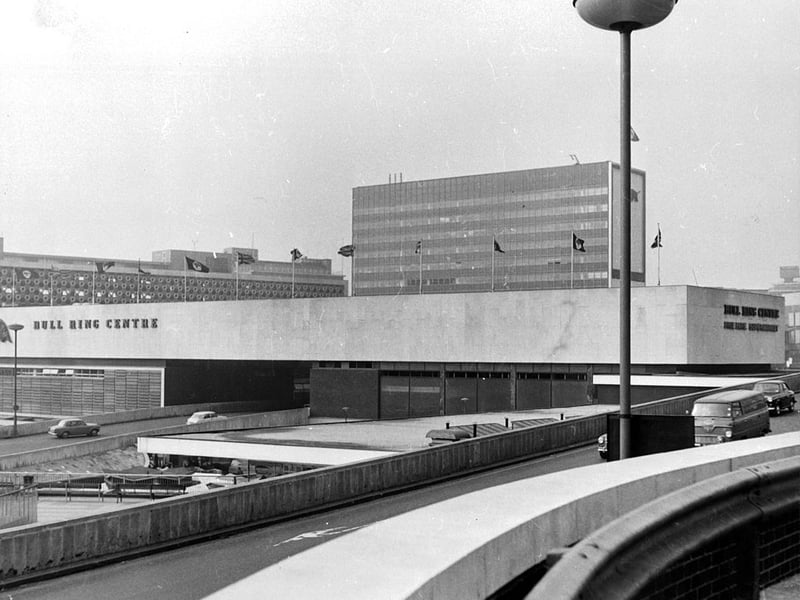 Cars drive through Birmingham city centre past the Bull Ring in 1965