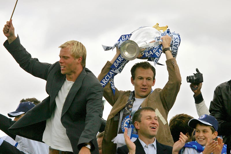  Chelsea striker Arjen Robben (R) holds the Barclay’s Premiership trophy aloft as he rides on an open top bus with Chelsea owner Roman Abramovich (front), Eidur Gudjohnsen (L)  and other teammates during a parade  in west London 22 May  2005. 