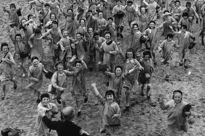 A crowd of happy children run toward Mr Brown, the superintendent of the Blackpool holiday home they are enjoying which offers a sea side break for poor children in the Manchester area, 16 August 1940.