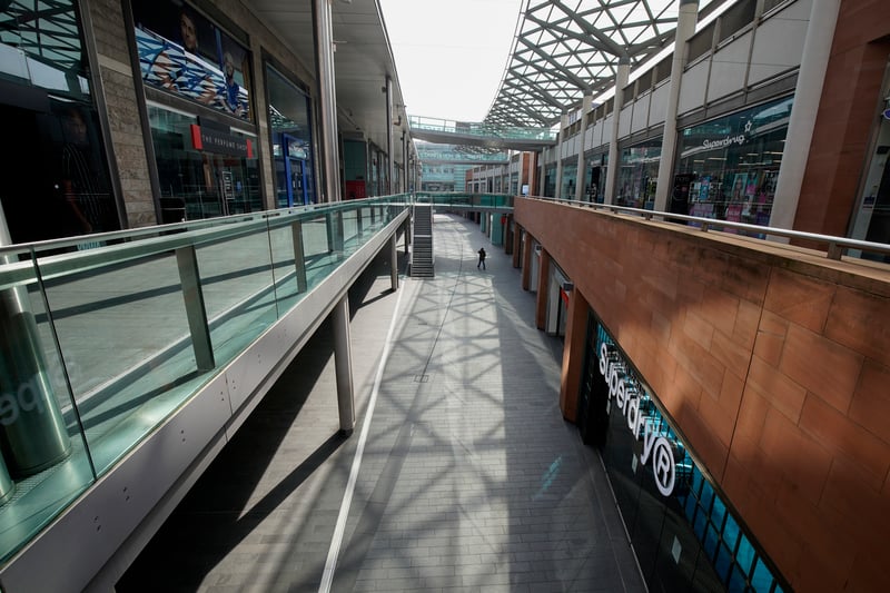 A solitary person walks through the Liverpool One shopping centre.