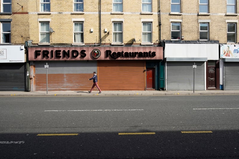 A solitary figure walks past shuttered shops on Smithdown Road.