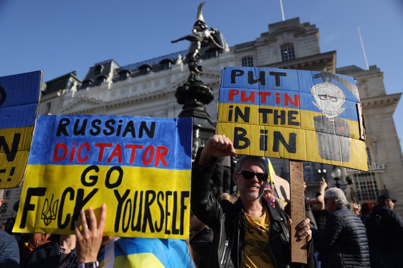 Placards reading ‘Put Putin in the bin’ and ‘Russian dictator - go f*** yourself’. Photo: Getty