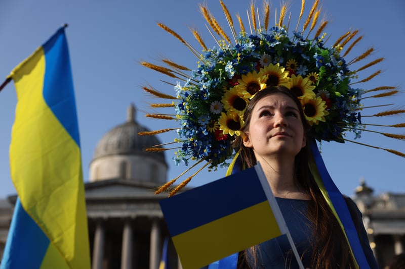 A protestor in a sunflower headdress holds a Ukrainian flag at Trafalgar Square. Photo: Getty
