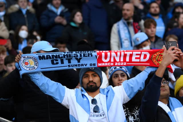 A Manchester City fan holds up a half and half scarf Credit: Getty