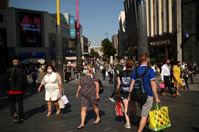 People wearing a face mask or covering due to the Covid-19 pandemic, walk along a busy shopping street in Birmingham city centre (Photo by OLI SCARFF/AFP via Getty Images)