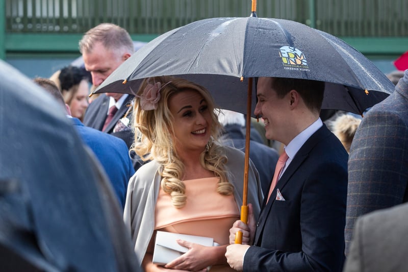 Racegoers shelter from the rain on the first day of the Aintree Randox Grand National.