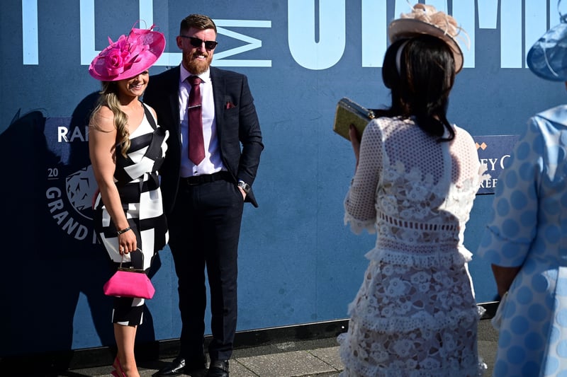 Racegoers pose for pictures in the sunshine upon their arrival at Aintree.