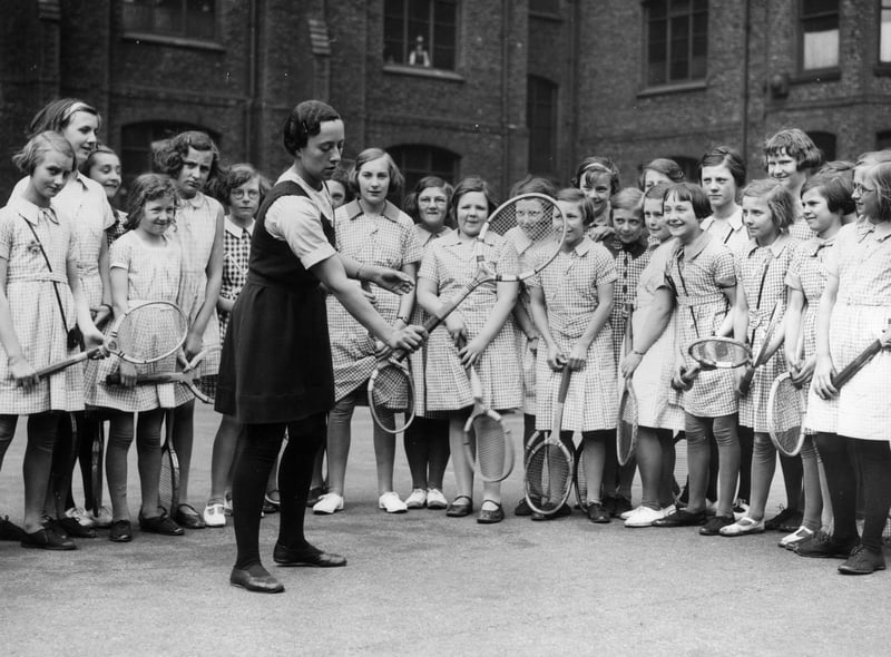 2 June 1936:  International hockey player Irene Dimmick, games mistress at Manchester High School, demonstrates tennis strokes to pupils.  