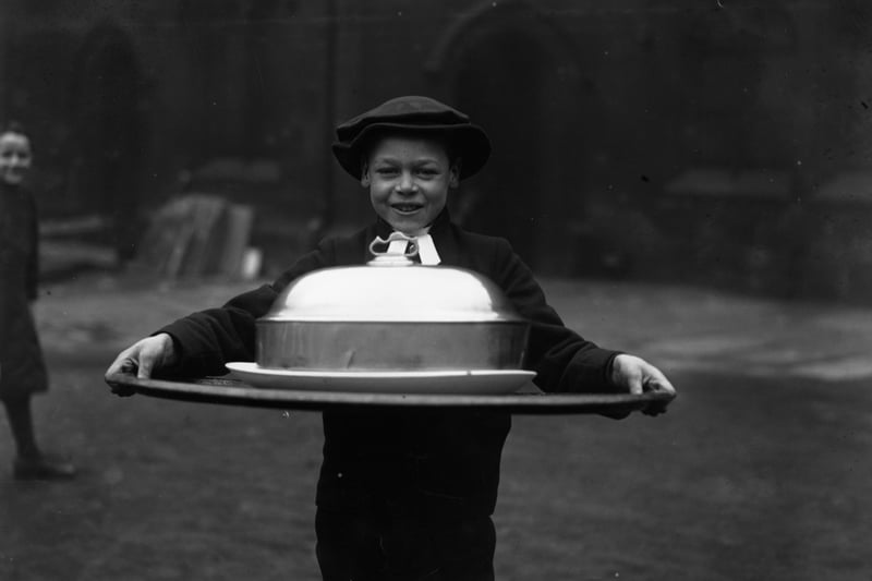 1926:  A boy carrying a large serving dish, again at Chethams School in Manchester