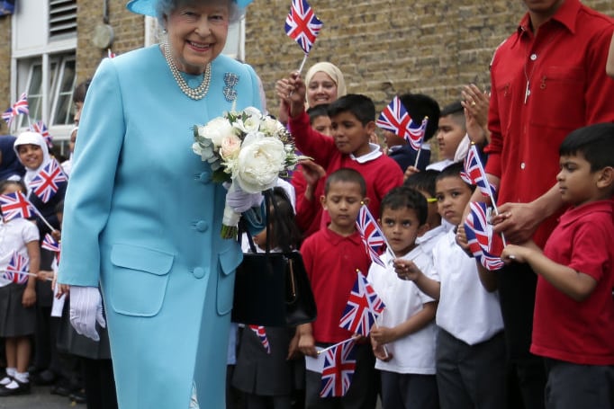 Queen Elizabeth II smiles as she walks past flag-waving school children after she tours Mayflower Primary School during a visit to Poplar in Tower Hamlets on June 15, 2017