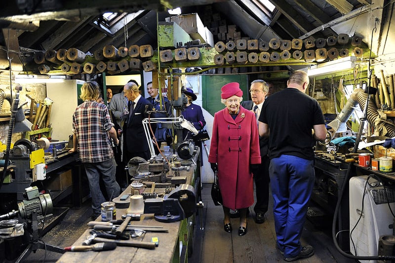  Queen Elizabeth II walks through a workshop at the Whitechapel Bell Foundry with her husband Prince Philip, Duke of Edinburgh, on March 25, 2009 in London