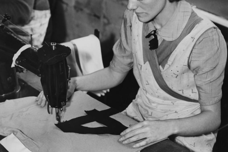 1939: A worker sewing a number onto the back of a Manchester City football shirt at a factory; numbered shirts have just been introduced for English League and Cup matches