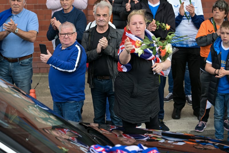 A woman throws flowers on the hearse as the cortege for Rangers kit man Jimmy Bell passes Ibrox stadium 