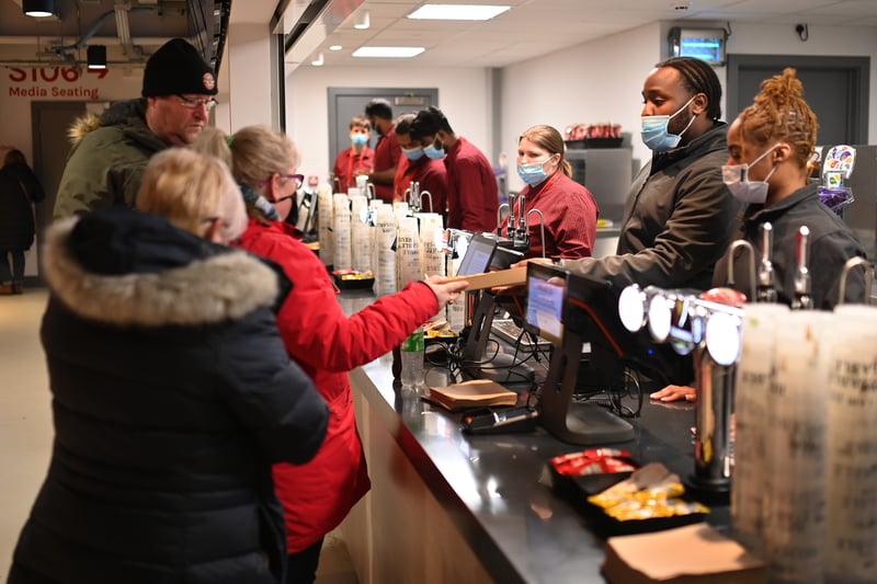 Staff wear face-masks as they serve food inside the stadium prior to the Premier League match between Brentford and Aston Villa at Brentford 