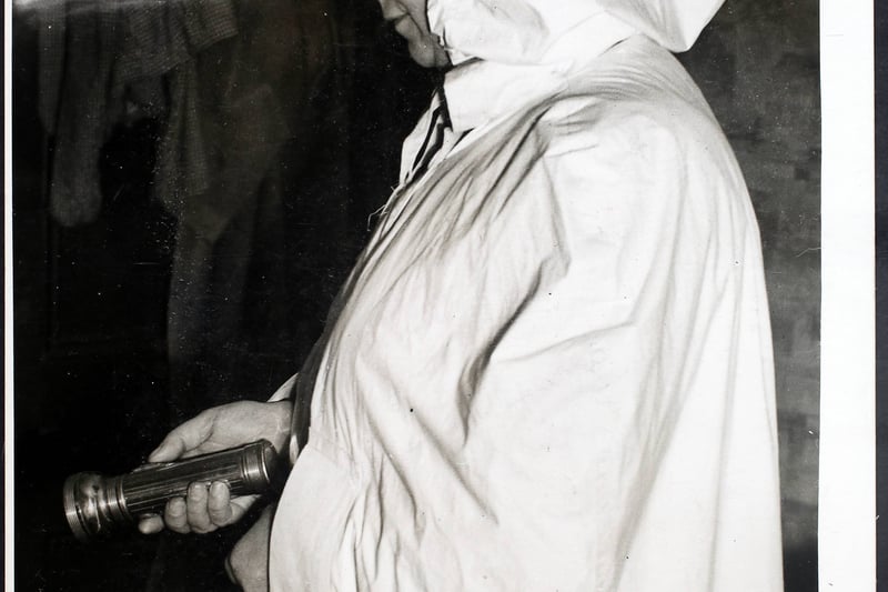 A Manchester maternity nurse wearing the new voluminous white cape and hood, and electric torch issued for black-outs, after many had near misses with traffic on night calls