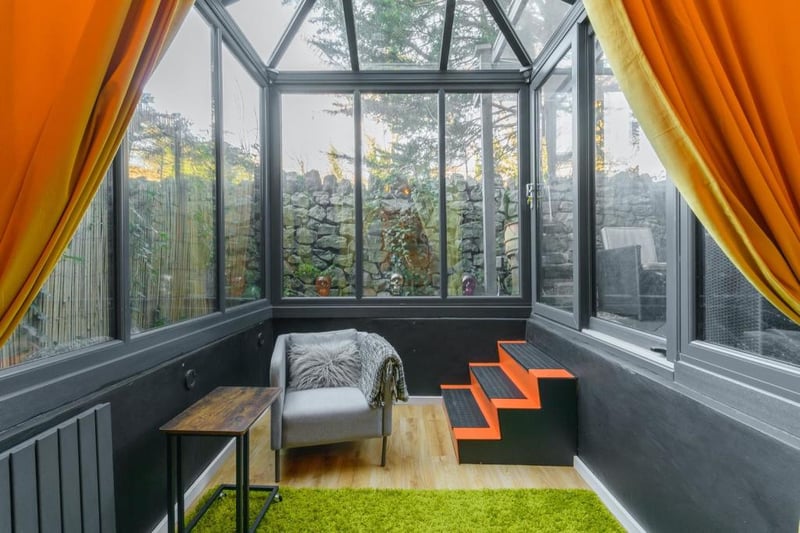 The conservatory really shows off the bold colour choices throughout the property with black walls, pops of bright orange and a sunken design