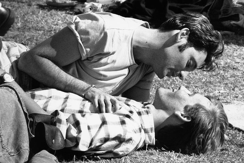 Two young men sharing a tender moment on the grass during a Gay Pride festival in London, 1996. 