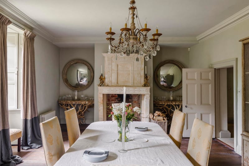 An 18th-century French limestone fireplace acts as a focal point and adds symmetry to the dining room.