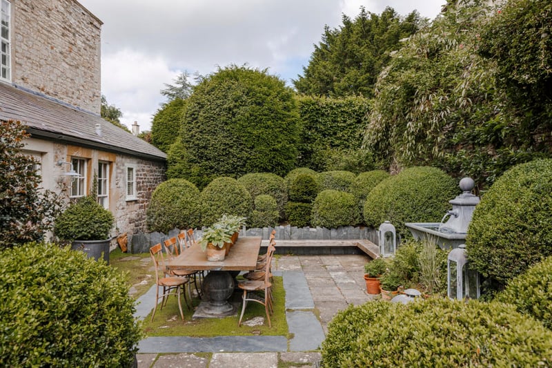 Doors open from the garden room to a large outdoor dining area bordered by plantings of Corsican mint and rambling roses.