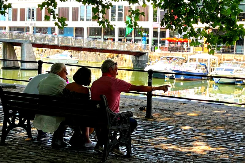 A group of people on Broad Quay wisely stick to the shade.