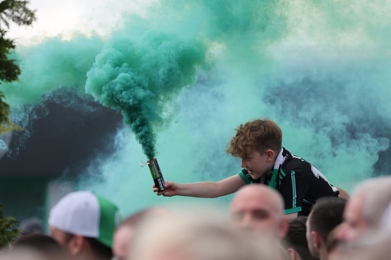 A young Celtic fans is held aloft as he lets off a green smoke bomb. 