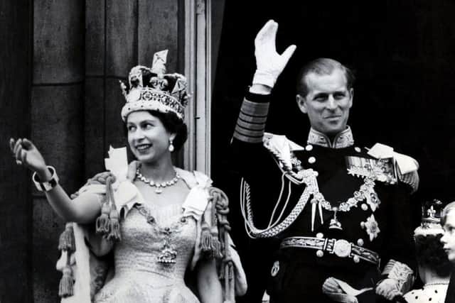 The Duke of Edinburgh with Queen Elizabeth II waving from the balcony to the onlooking crowds around the gates of Buckingham Palace after her Coronation in June 1953. Picture: PA.