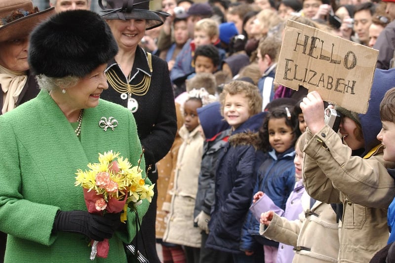 Queen Elizabeth II walks past children from St Michael on the Mount School  while Django Reeves Short aged 10 holds his ‘Hello Elizabeth’ sign and takes a picture. The Queen experienced cake-making, bricklaying and hip-hop dance during a visit to Bristol. The Monarch was touring The Park in Knowle West.