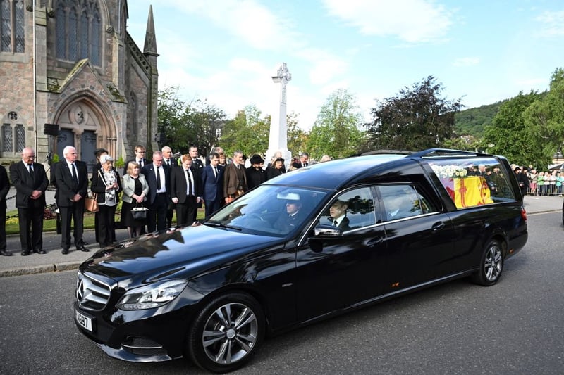 Members of the public pay their respects as the hearse carrying the coffin of Queen Elizabeth II is driven through Ballater.

