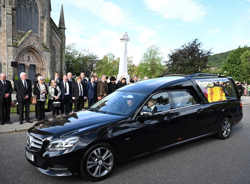 Members of the public pay their respects as the hearse carrying the coffin of Queen Elizabeth II is driven through Ballater.
