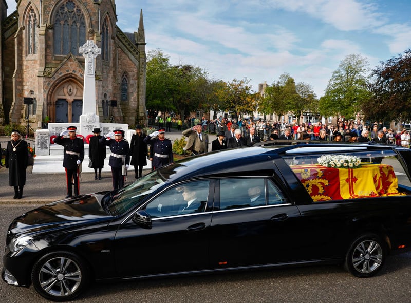  People salute as others gather in tribute as the cortege carrying the coffin of the late Queen Elizabeth II passes by.