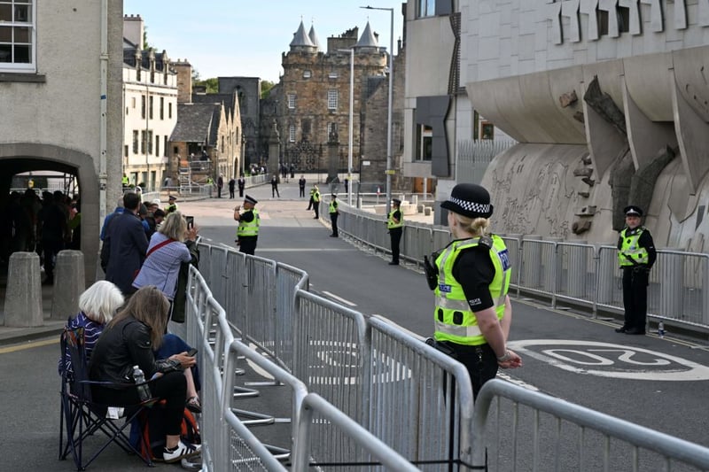 Police officers stand guard as members of the public begin to gather outside of the Palace of Holyroodhouse in Edinburgh, as preparations are made for the arrival of the coffin of Queen Elizabeth II 
