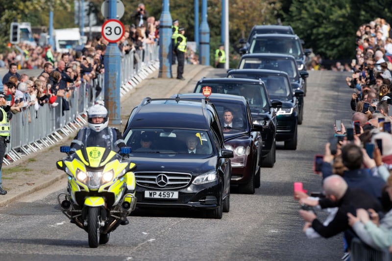 Crowds gather as the cortege carrying the coffin passes over the King George VI bridge in Aberdeen
