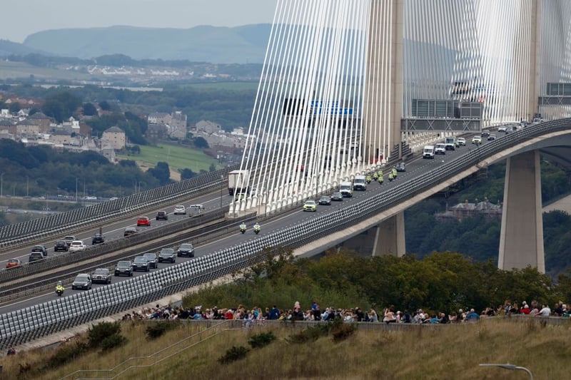 People gather in tribute as the cortege carrying the coffin passes on the Queensferry Crossing road bridge over the Forth Estuary  in North Queensferry.