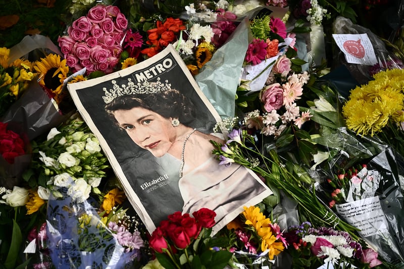 A copy of the Metro newspaper displaying a stunning image of the Queen in a white dress and jewelled tiara in Green Park surrounded by flowers.