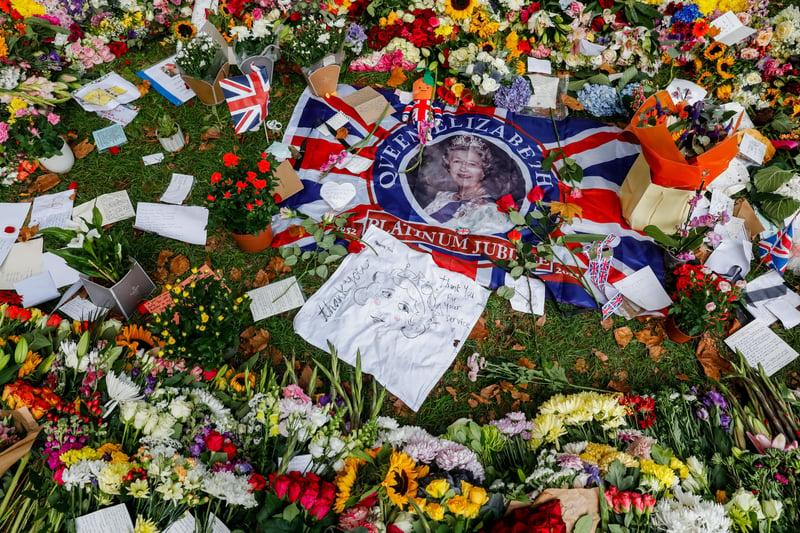 Queen Elizabeth on a British flag laid in the centre of a arrangement of flowers in Green Park.