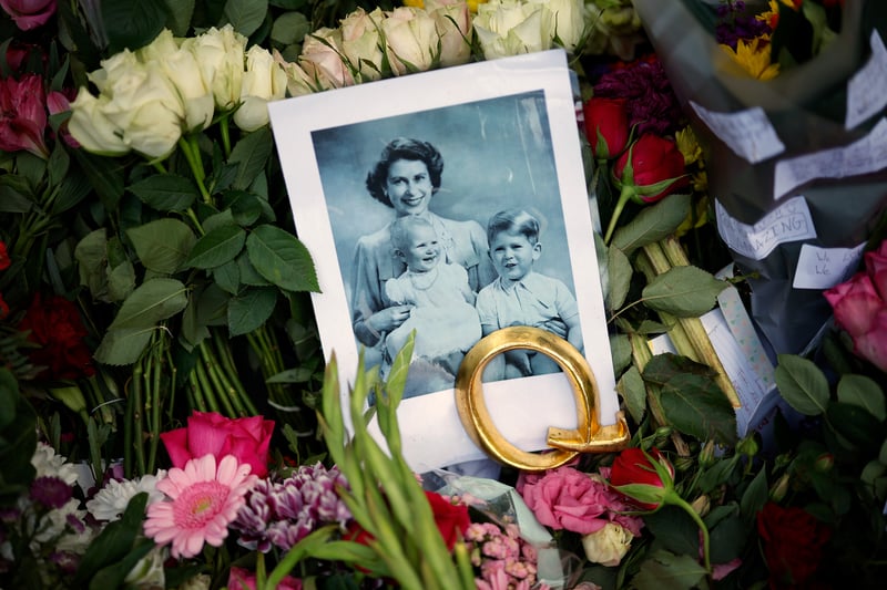A photograph of Queen Elizabeth and two of her young children - adorned with a golden letter Q.