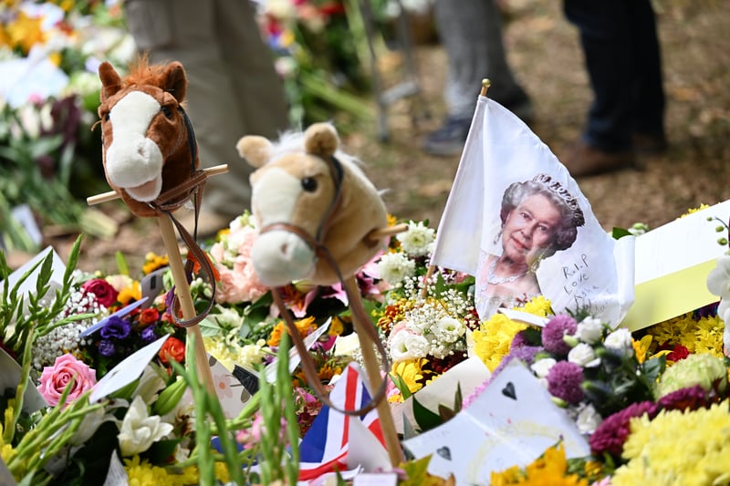 Two soft toy horse heads alongside a white flag depicting Queen Elizabeth - who famously adored her horses and horse racing.