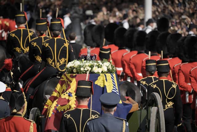 The coffin of Queen Elizabeth II, draped in the Royal Standard, is carried on a horse-drawn gun carriage of the King's Troop Royal Horse Artillery, during the ceremonial procession from Buckingham Palace to Westminster Hall, London, where it will lie in state ahead of her funeral on Monday