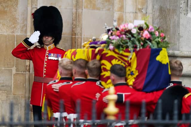 The coffin of Queen Elizabeth II, draped in the Royal Standard with the Imperial State Crown and the Sovereign's orb and sceptre, is carried into Westminster Abbey during State Funeral. Picture date: Monday September 19, 2022.