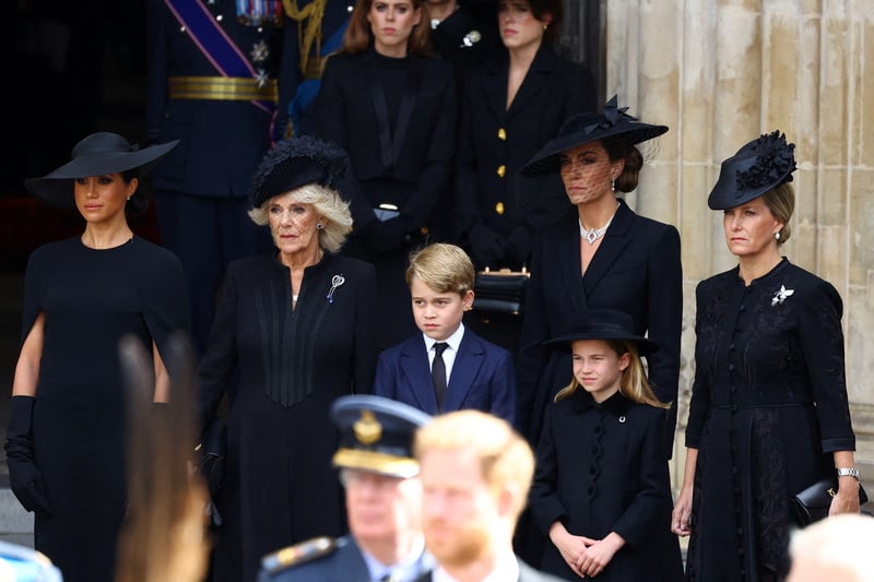 Meghan, Duchess of Sussex, Queen Camilla, Prince George, Princess Charlotte, Princess of Wales and Sophie, Countess of Wessex stand outside Westminster Abbey.