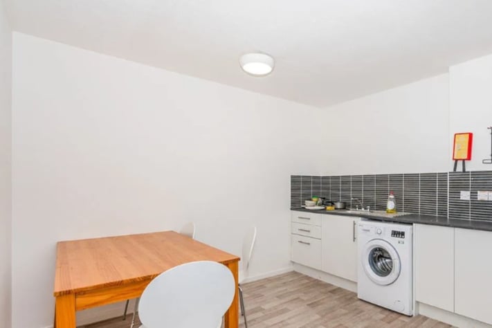 The kitchen/dining area features laminate flooring and a washing machine.