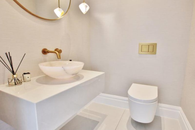 Downstairs, there is a modern toilet, with a beautiful marble sink and gold accents. 