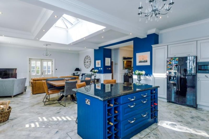 The kitchen island serves as wine storage, as well as a place to prepare food. The pop of blue adds a quirky feel to the room and the skylight provides masses of natural light
